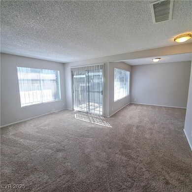 Empty room with carpet floors, a textured ceiling,