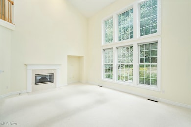 Unfurnished living room featuring carpet flooring, a high end fireplace, and a towering ceiling