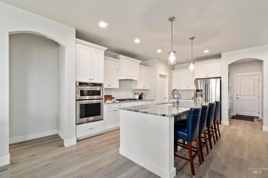 Kitchen featuring arched walkways, stainless steel appliances, a kitchen bar, recessed lighting, and backsplash