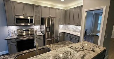 Kitchen featuring gray cabinetry, stainless steel appliances, light stone counters, and backsplash