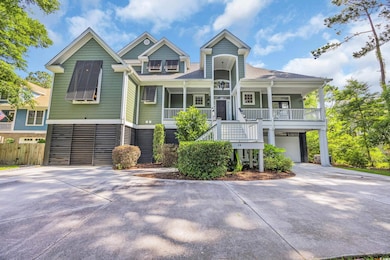 Beach home featuring covered porch, driveway, stairs, a garage, and a shingled roof