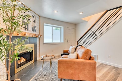 Living area featuring a fireplace, baseboards, stairs, wood finished floors, and recessed lighting