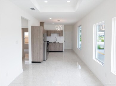 Kitchen featuring light countertops, recessed lighting, a tray ceiling, freestanding refrigerator, and pendant lighting