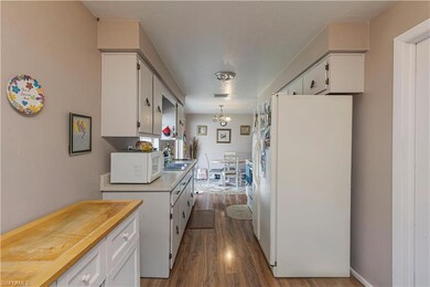 Kitchen with white appliances, white cabinetry, dark wood finished floors, and a chandelier