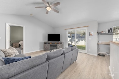 Living room featuring light wood-style floors, lofted ceiling, a ceiling fan, and a textured ceiling