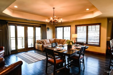 Dining room with a tray ceiling, french doors, recessed lighting, dark wood-style flooring, and a chandelier