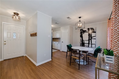 Dining space with a chandelier, wood finished floors, and crown molding