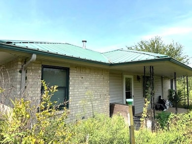 View of front facade featuring a metal roof, a patio area, and brick siding