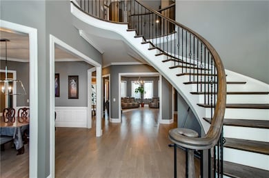 Stairway featuring a chandelier, wood finished floors, ornamental molding, and a high ceiling