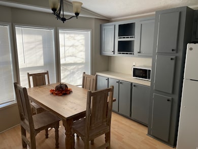 Dining area with light wood-type flooring, vaulted ceiling, and a chandelier