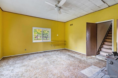 Unfurnished room featuring carpet floors, stairs, and a ceiling fan