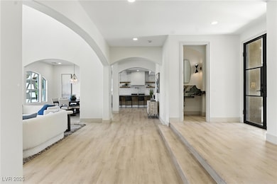 Hall with arched walkways, wood finished floors, a