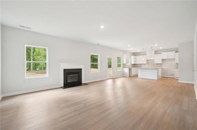 Unfurnished living room with plenty of natural light, recessed lighting, a glass covered fireplace, and light wood-type flooring