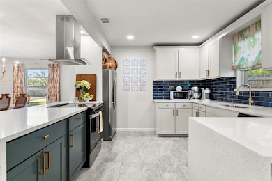 Kitchen with plenty of natural light, light stone counters, white cabinetry, and recessed lighting