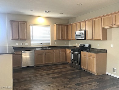 Kitchen featuring appliances with stainless steel finishes, dark wood-style flooring, brown cabinetry, and recessed lighting