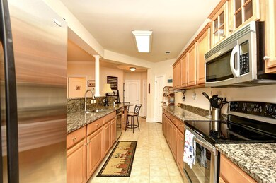 Kitchen featuring appliances with stainless steel finishes, light stone counters, glass insert cabinets, and light tile patterned floors