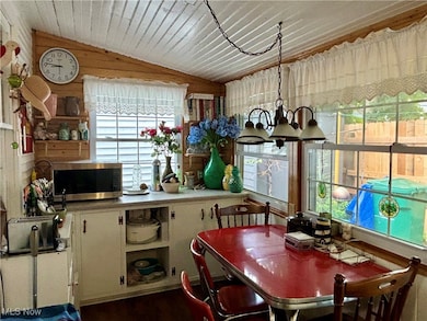 Kitchen with open shelves, wood walls, vaulted ceiling, light countertops.