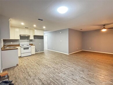 Kitchen with white electric stove, visible vents, light wood-style floors, under cabinet range hood, and a sink