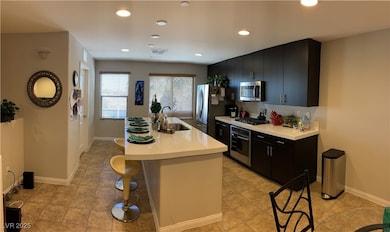 Kitchen island with large drop in sink, recessed lighting, a breakfast bar, and appliances with stainless steel finishes