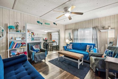 Living room with ceiling fan, wood walls, and wood