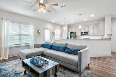 Living area with healthy amount of natural light, dark wood-style floors, a ceiling fan, and recessed lighting
