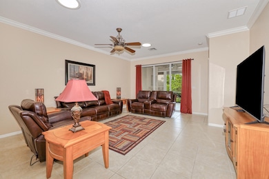Living room with ornamental molding, ceiling fan, and light tile patterned flooring