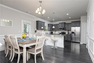 Dining space with a chandelier, dark wood-type flooring, crown molding, and recessed lighting