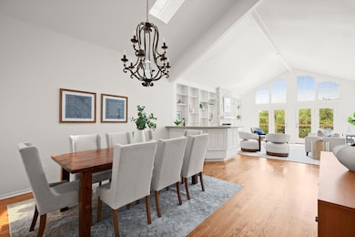 Dining room with beamed ceiling, high vaulted ceiling, light wood-style flooring, and a chandelier