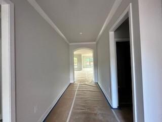 Hallway featuring arched walkways, ornamental molding, and concrete flooring
