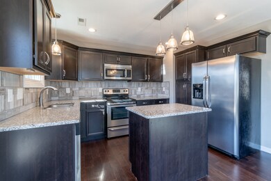 Kitchen also features stainless steel appliances and tile backsplash.