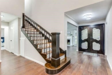 Foyer entrance with wood finished floors, stairs, french doors, and a fireplace