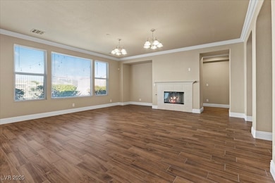 Family room featuring ornamental molding, a tiled fireplace, tile  floors, and a chandelier