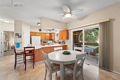 Dining room featuring ceiling fan, a textured ceiling, and baseboards
