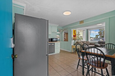 Kitchen with light tile patterned flooring, appliances with stainless steel finishes, open floor plan, and white cabinets