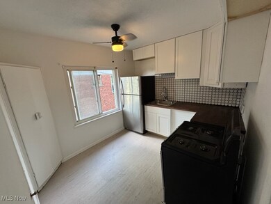 Kitchen featuring light wood-type flooring, ceiling fan, white cabinetry, and stainless steel refrigerator