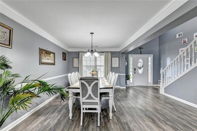 Dining room featuring a chandelier, wood finished floors, crown molding, and stairs
