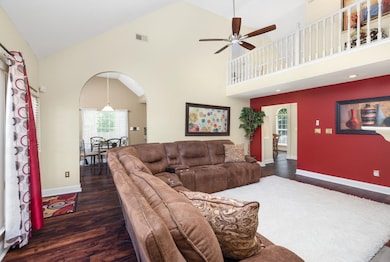 Living room featuring arched walkways, wood finished floors, healthy amount of natural light, ceiling fan, and high vaulted ceiling