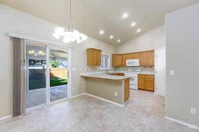Kitchen featuring white appliances, a chandelier, light countertops, a peninsula, and pendant lighting