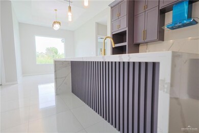 Kitchen with light tile floors, a tray ceiling, kitchen peninsula, and pendant lighting