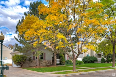View of property hidden behind natural elements with a front yard and brick siding