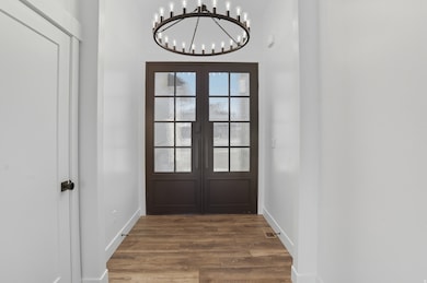 Doorway to outside featuring wood finished floors, a chandelier, and french doors