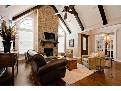 Living Room. Features wall to ceiling stone fireplace, rustic wood beams, speakers, white trim and baseboards