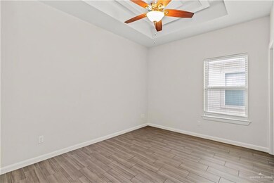 Spare room featuring a tray ceiling, light hardwood / wood-style floors, and ceiling fan