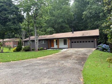 Ranch-style home featuring driveway, a garage, and a front yard