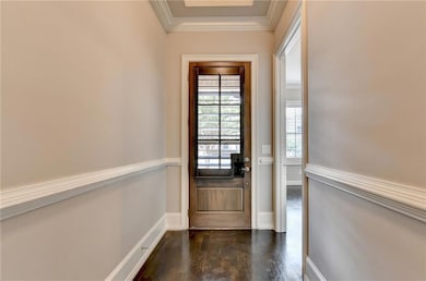 Doorway with crown molding and wood finished floors