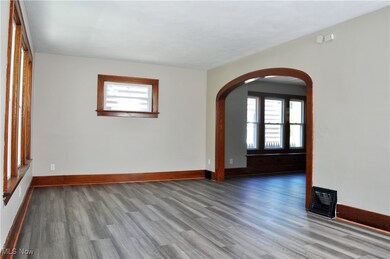 Unfurnished room featuring arched walkways and wood finished floors