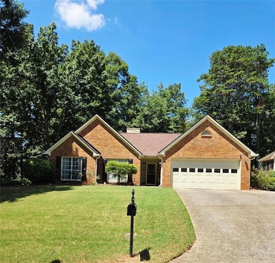 Single story home with concrete driveway, an attached garage, a front lawn, brick siding, and a chimney