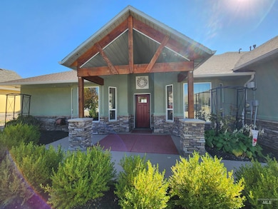 Property entrance with stucco siding, a shingled roof, stone siding, and covered porch