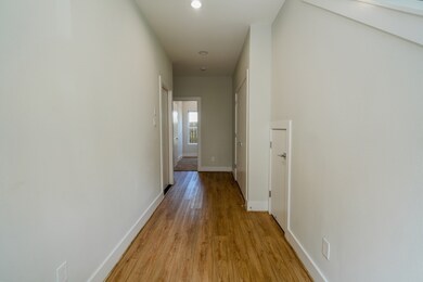 Bright entry hallway with high ceilings and wood flooring. Clean, neutral tones create a welcoming and spacious feel.