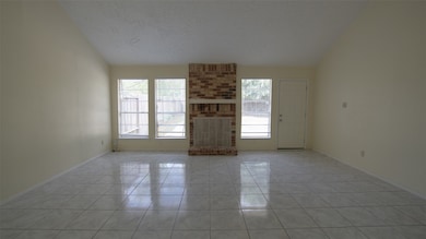The spacious living room features high ceilings, plenty of natural light, and tile flooring. A back door provides access to the rear of the property.